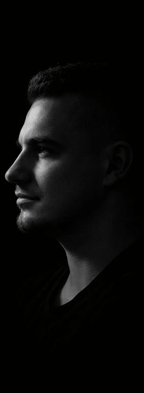 A low-key light photograph of Daniel, taken from the side.